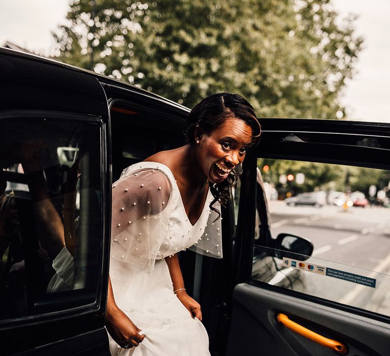 Bride getting out of a London Black Cab in a layered skirt and pearl top 