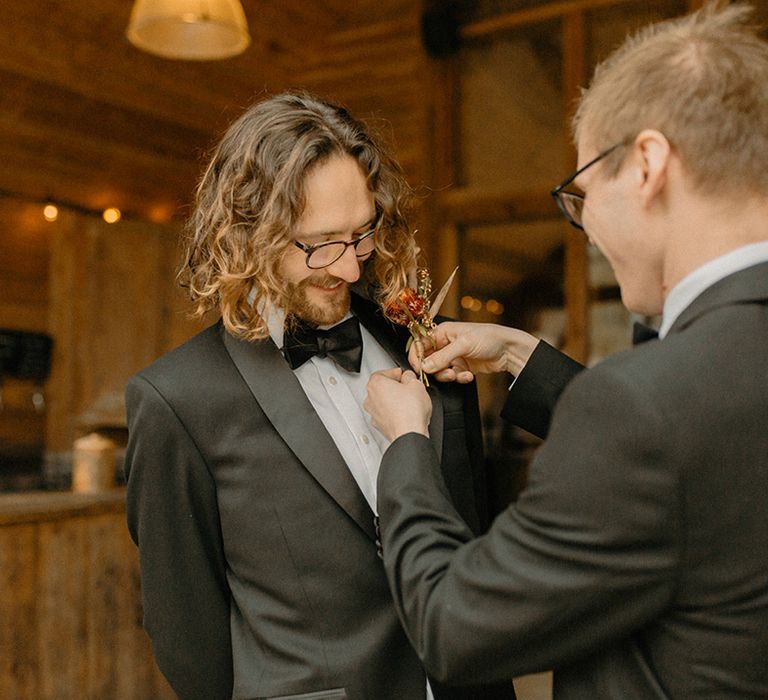 Groomsmen attaches the groom's dried flower buttonhole