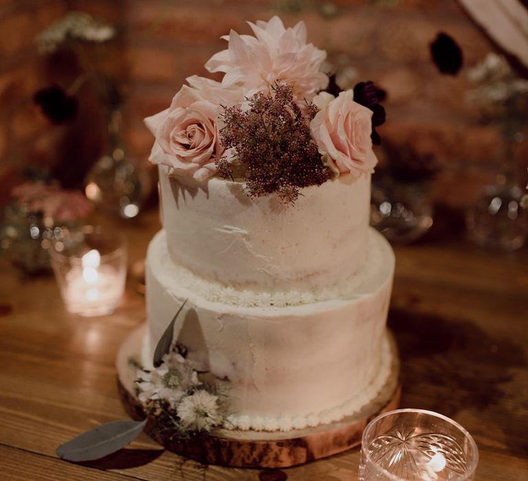 Two tier white frosted wedding cake with pink roses and dahlias for decoration