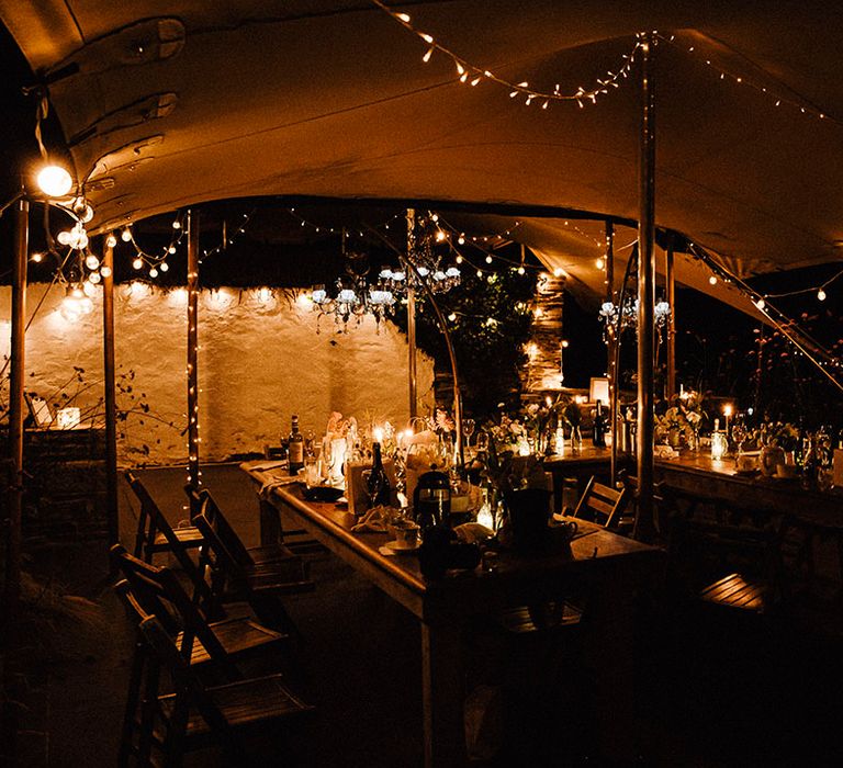 Fairy lights and candles decorate the outdoor reception area under canopy during the night time