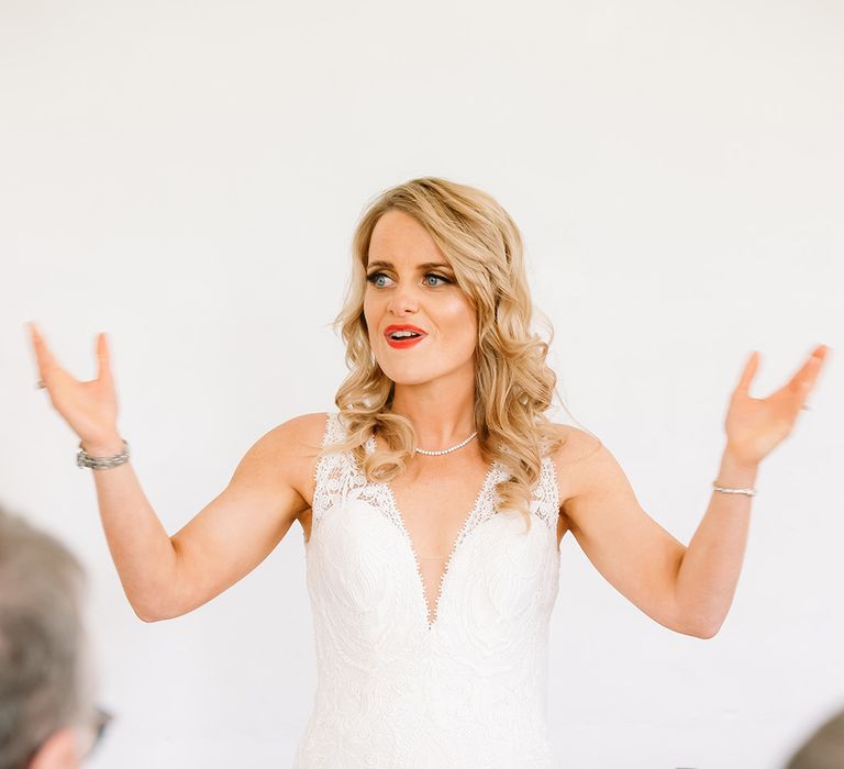 Bride in v-neck lace wedding dress with curled blonde hair and red lipstick 