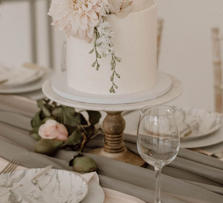 Traditional white wedding cake with two tiers and decorated with large white flower 