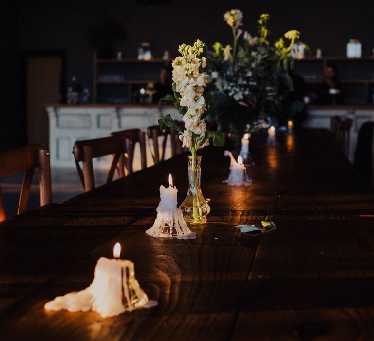 White pillar candles melting with flowers decorating the reception tables