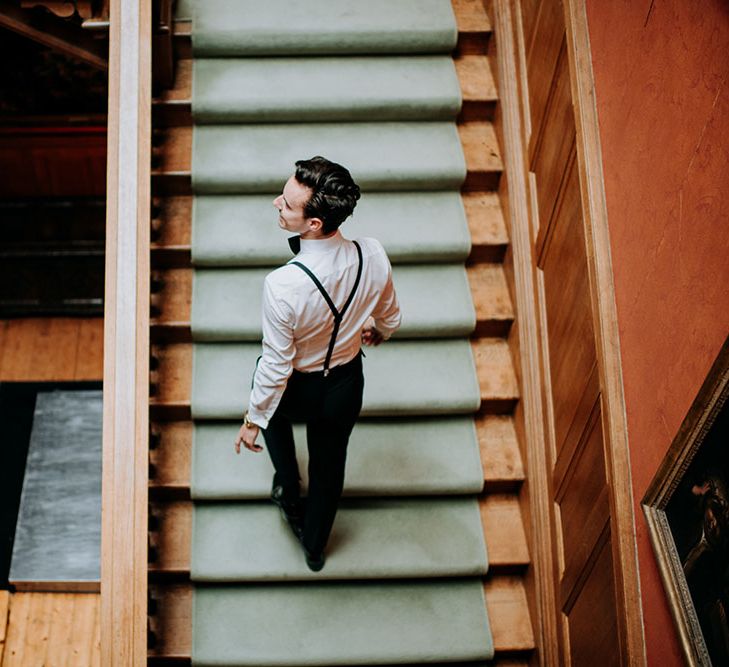 Groom walks up grand staircase on the morning of his wedding day at Birdsall House 