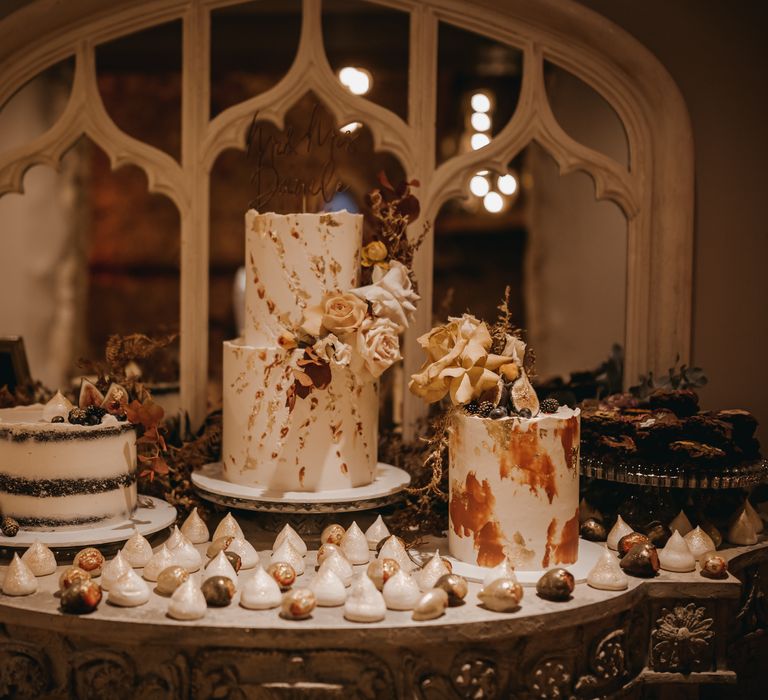 Luxury dessert table with three cakes finished with meringue kisses dusted with glitter and dried floral decoration   