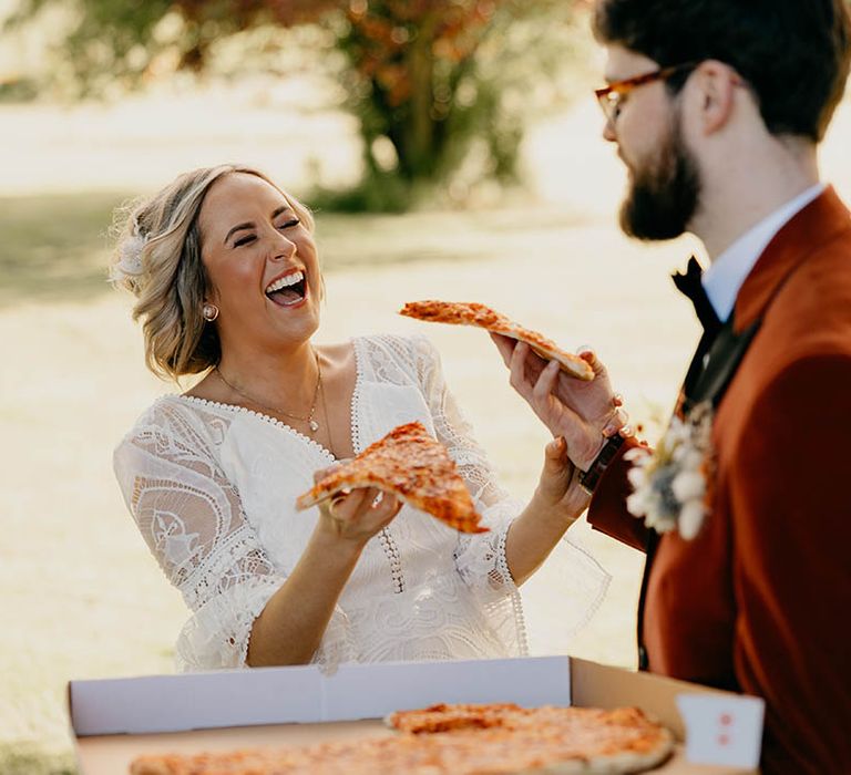 Bride and groom are surprised with a box of pizza as hey take their couple photos