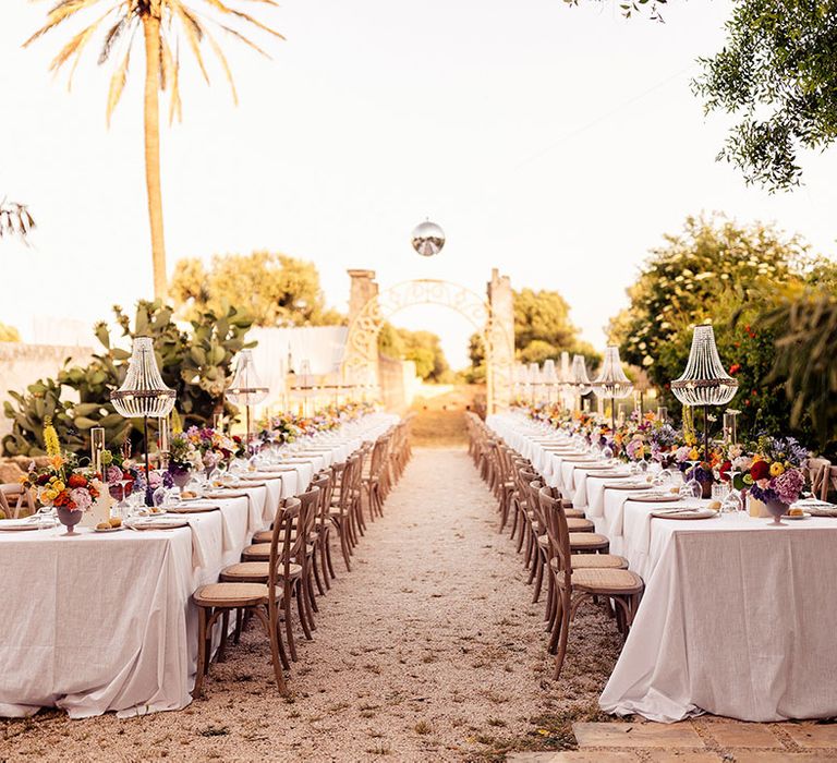 Puglia destination wedding with chandelier installations over the outdoor banquet tables for the reception 