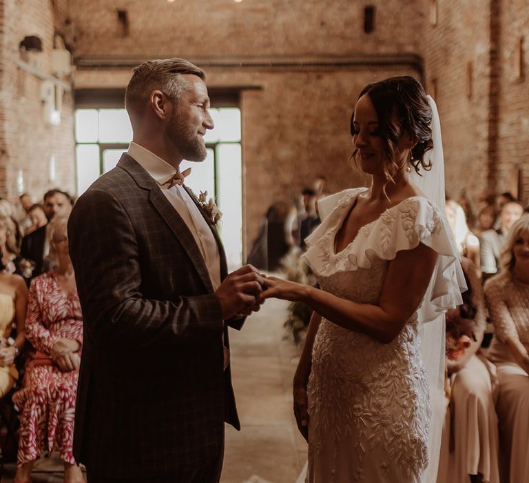 Groom in a grey suit with the bride in a bespoke Emma Beaumont embroidered wedding dress at their barn ceremony 