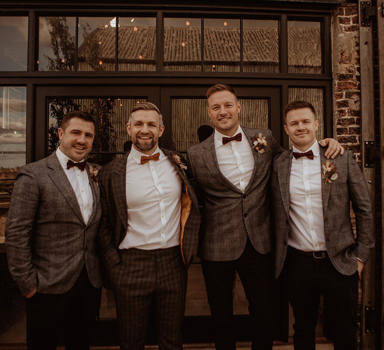 Groom and groomsmen in grey suits with bow ties for the rustic luxe barn wedding 