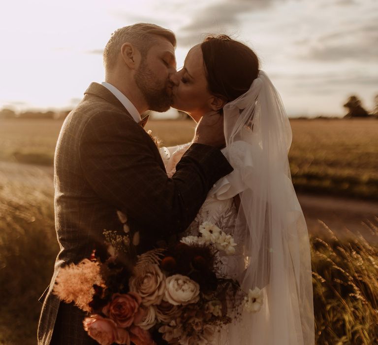 Bride and groom share a kiss during golden hour for their couple portraits 