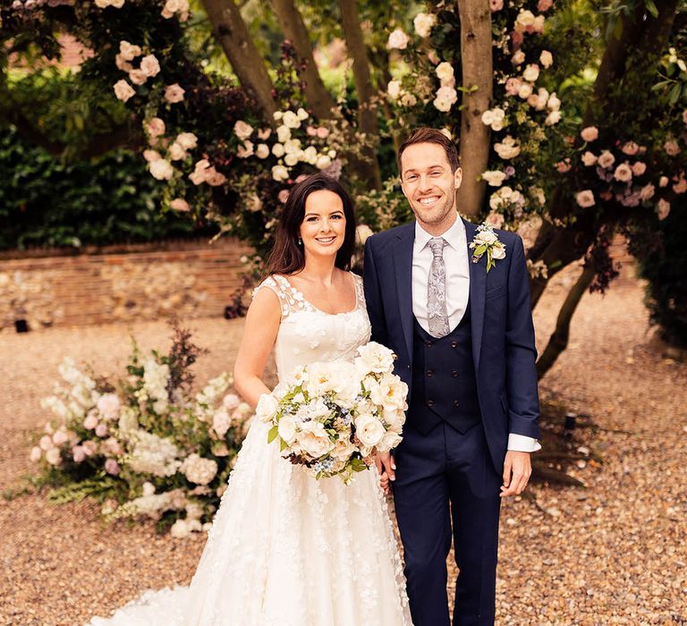 Groom in a blue three piece suit with a patterned tie standing with the bride in a Phillipa Lepley wedding dress