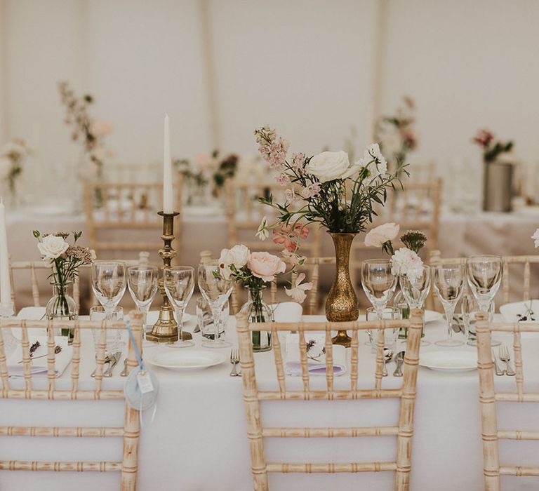 Classic and romantic white and pink wedding tablescape with taper candles and small flower arrangements 