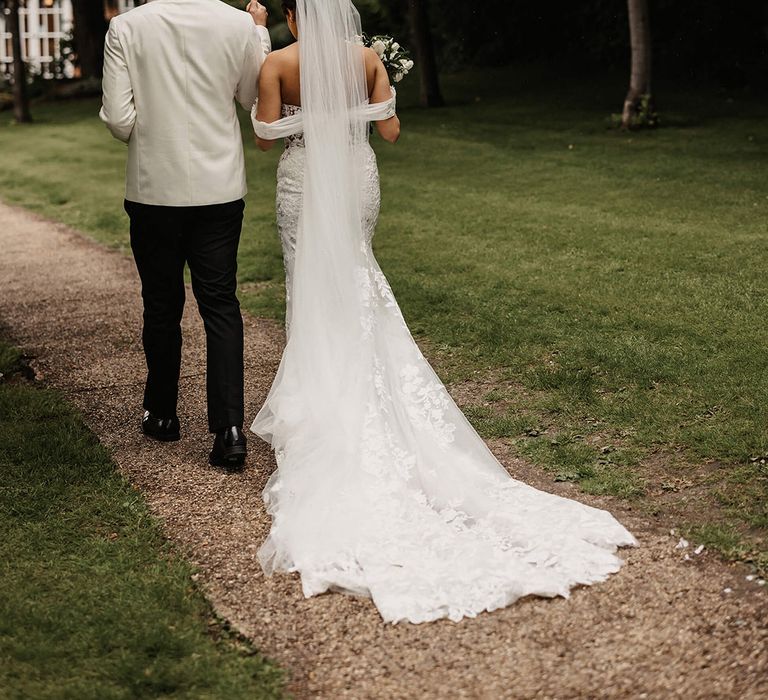 Bride and groom walk underneath an umbrella together on their wedding day at The Orangery in Kent 