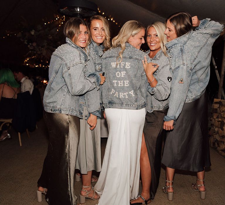 Bride and bridesmaids in blue denim jackets decorated with pearls and a personalised cover up for the bride 