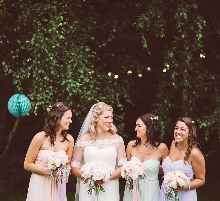 Bridesmaids in strapless pastel dresses with pink and white rose bouquets 