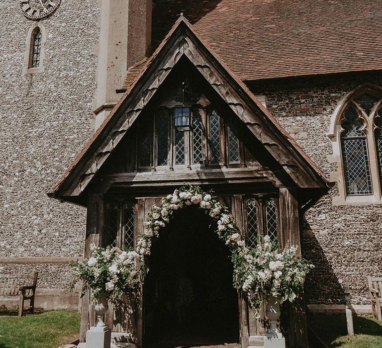 Simple white flower arch over the entrance of the church 