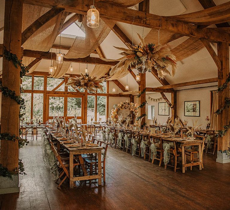 Nancarrow Farm rustic barn wedding venue with exposed wooden beams, fairy lights, neon sign, ballon arch, disco balls, and pampas grass flower installation 