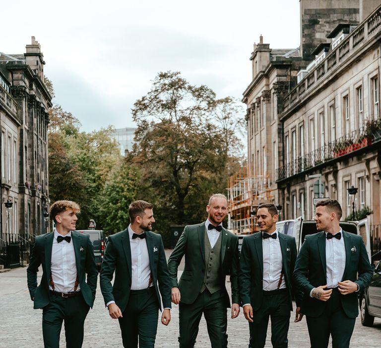 Groom & his groomsmen wear deep green suits with black bow-ties and brogues 