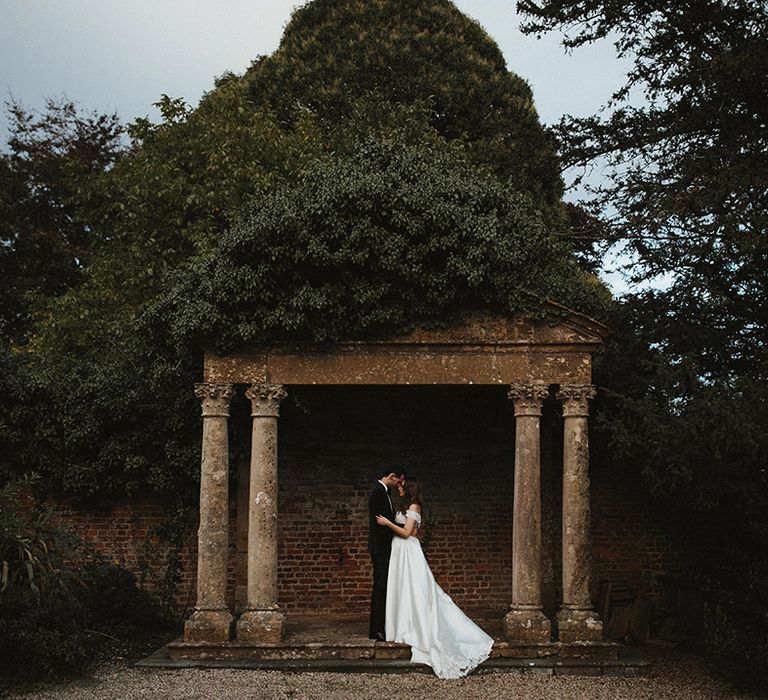 A classic black tie wedding at Brympton House with the bride and groom posing together 