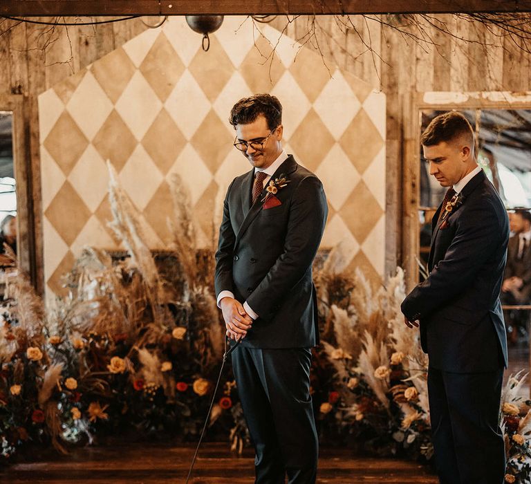 Groom wears bespoke suit and holds sausage dog at The Dreys wedding venue