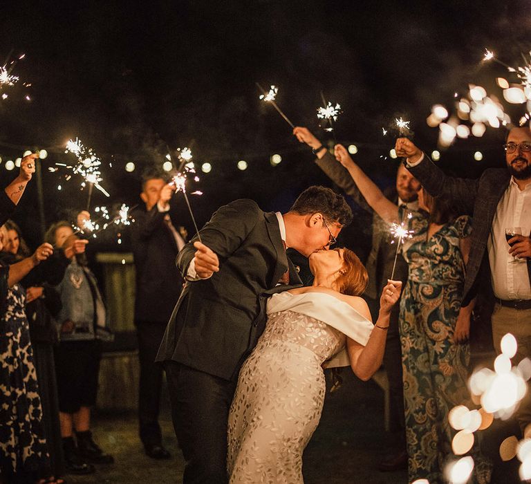 Groom kisses his bride during sparkler exit 