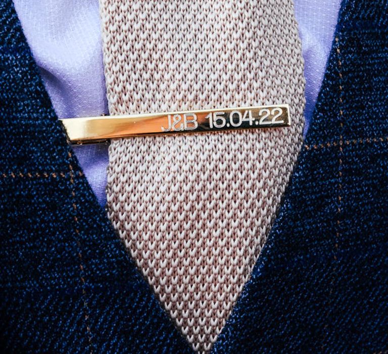 Ivory wedding tie with personalised gold tie clip with the groom's initials and the wedding date 