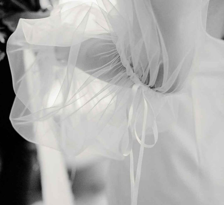 Close up shot of large dramatic long sheer puff sleeves on satin wedding dress