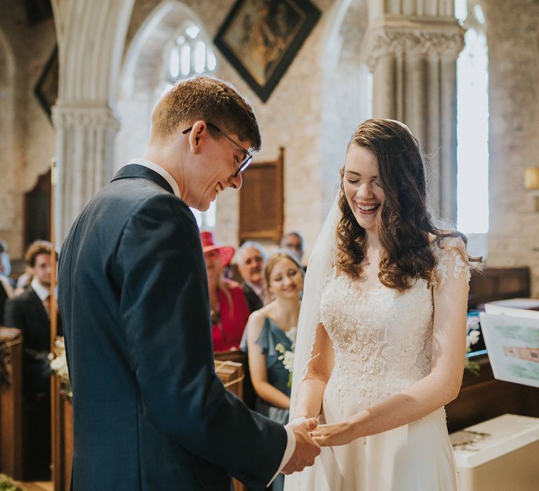 Groom puts on the wedding ring onto the bride's fingers for the Christian church ceremony