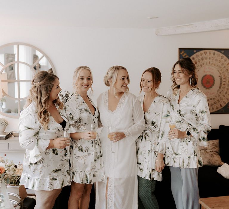 Bridesmaids in patterned silk bridesmaid robes with the bride in a long white lace trim robe 