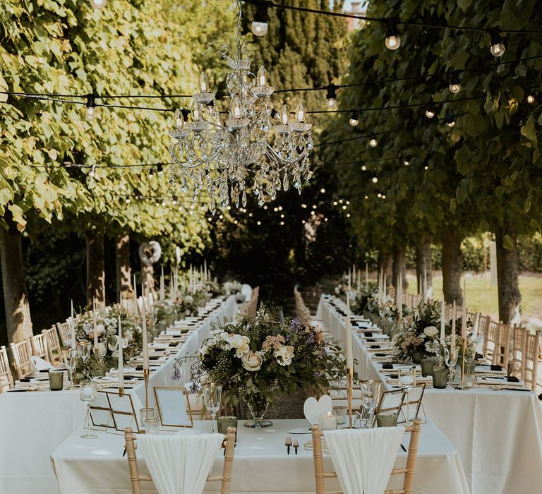 Sweetheart top table for the bride and groom at their outdoor wedding breakfast with white drapery chair back decor 