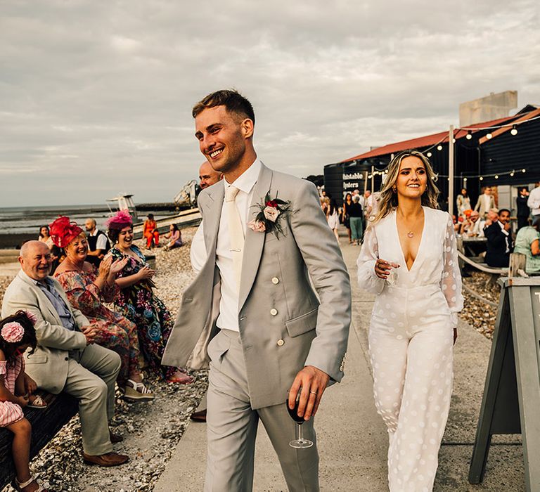 groom in a tailor-made King & Allen light grey suit and bride in a long sleeve Nikeen Asar jumpsuit at East Quay wedding 