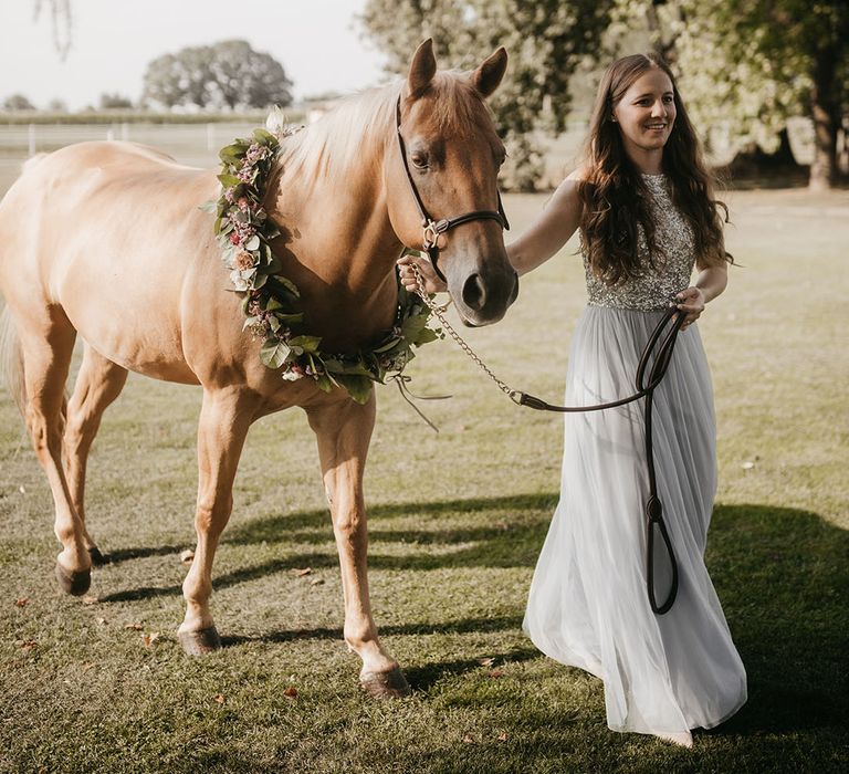 horse wearing a flower collar as the ring bearer at outdoor wedding ceremony 