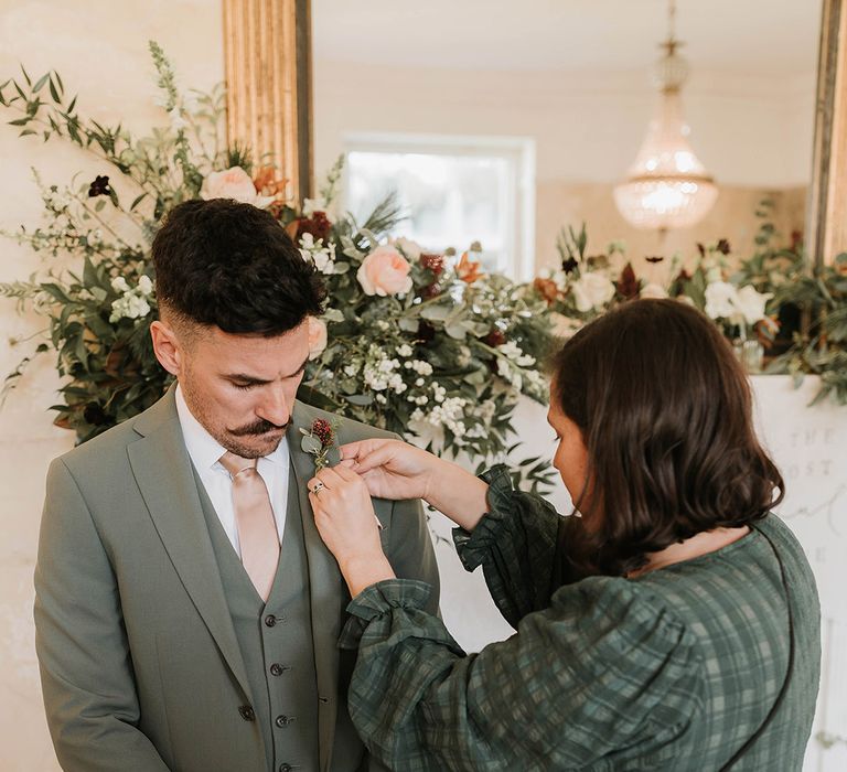 Groom in green three piece wedding suit with pale pink tie and pocket square 