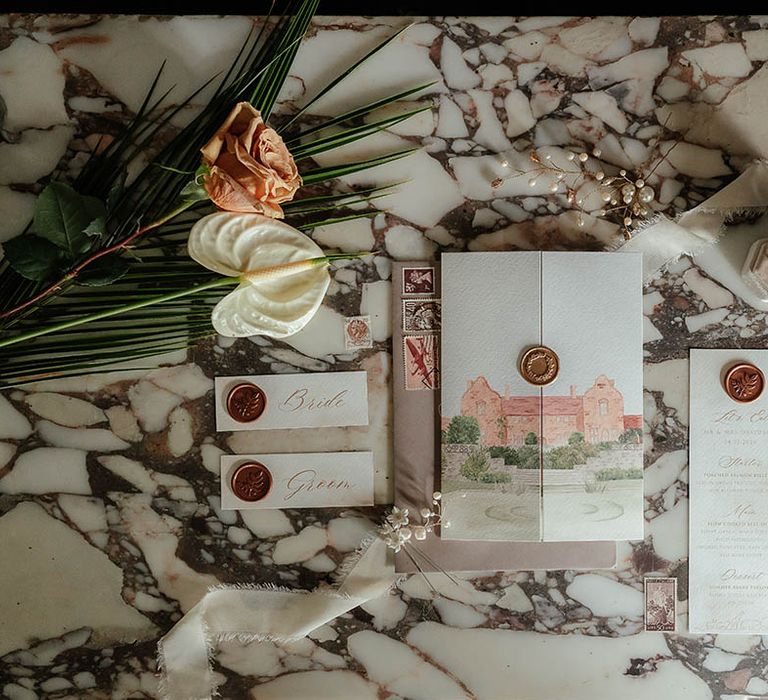 Wedding stationery flatlay with custom watercolour art and gold wax seals 