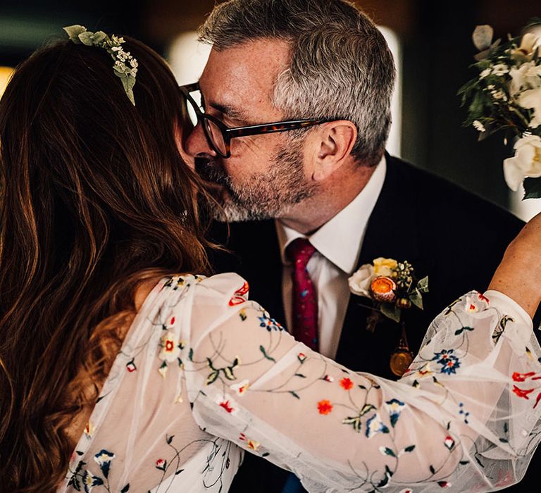 Father of the bride kisses the bride on the cheek 