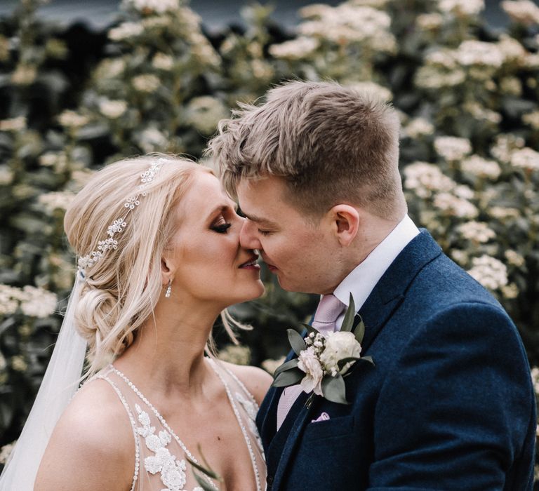 Bride and groom kissing at barn wedding with vintage wedding car hire