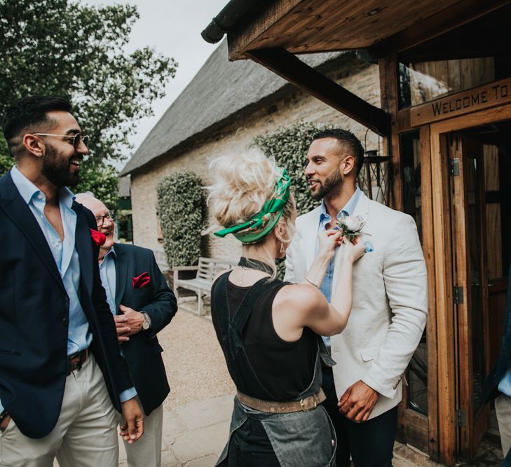 Groom gets ready for wedding ceremony with friend straightening his button hole