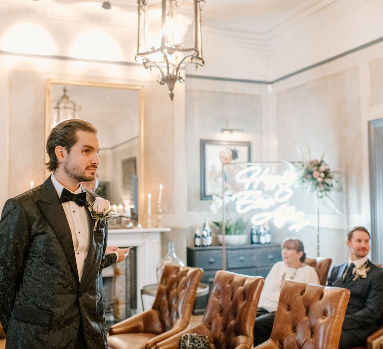 Groom waiting for his bride with neon happily ever after sign