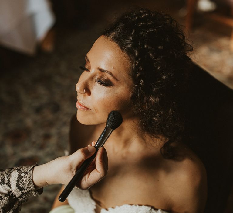 Bride with brown curly hair having her makeup up done with brown glitter eyeshadow 