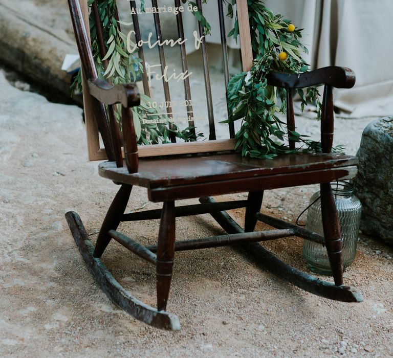 Wedding welcome perspex signs rests on old wooden rocking chair.