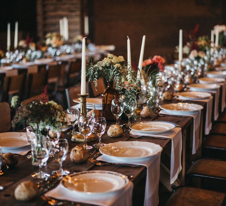 Place setting with different tableware and napkins on a banquet table with floral centrepieces