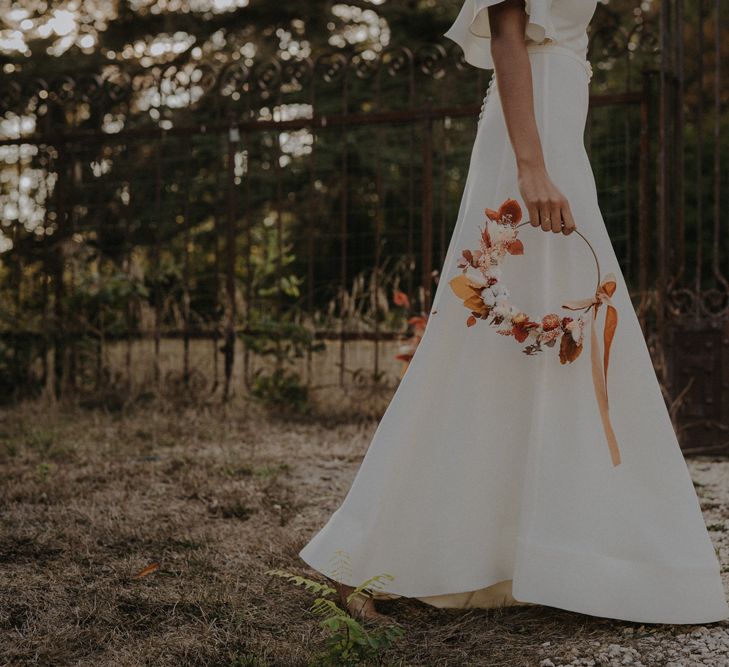 Bride in an a-line wedding dress holding an autumn flower hoop 