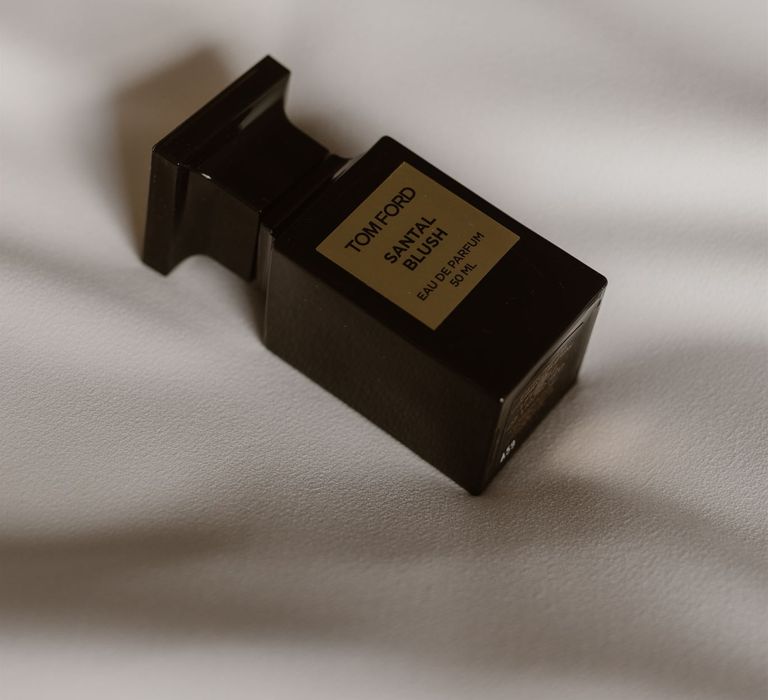 Black bottle of Tom Ford Santal Blush Eau De Parfum on white bedspread