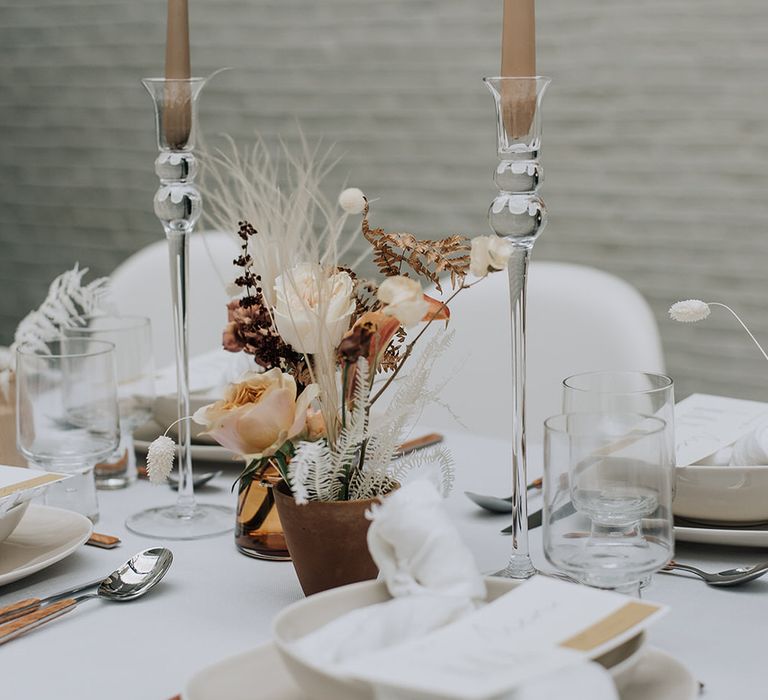 Neutral tapered candlesticks in glass holders with mini dried floral centrepieces