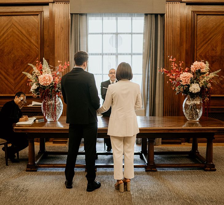 Bride & groom stand with their back to the camera during wedding ceremony