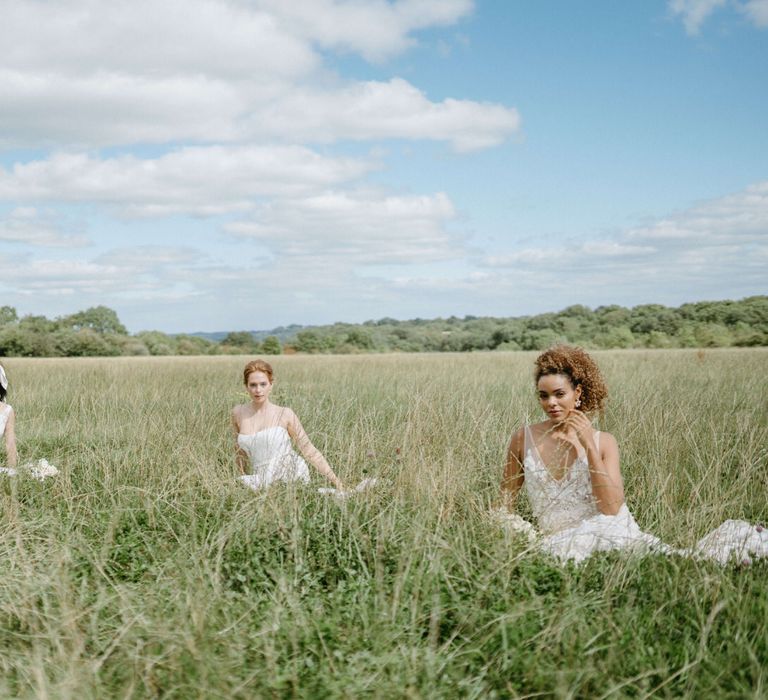 Three boho style brides sitting in the fields at Berwick Lodge