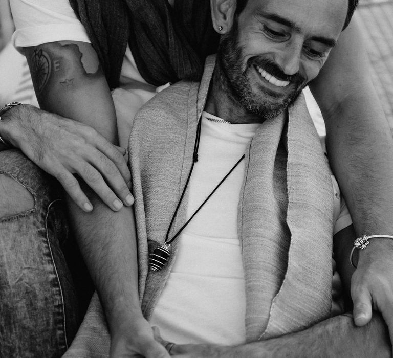 Black & white image of grooms laughing together during engagement session