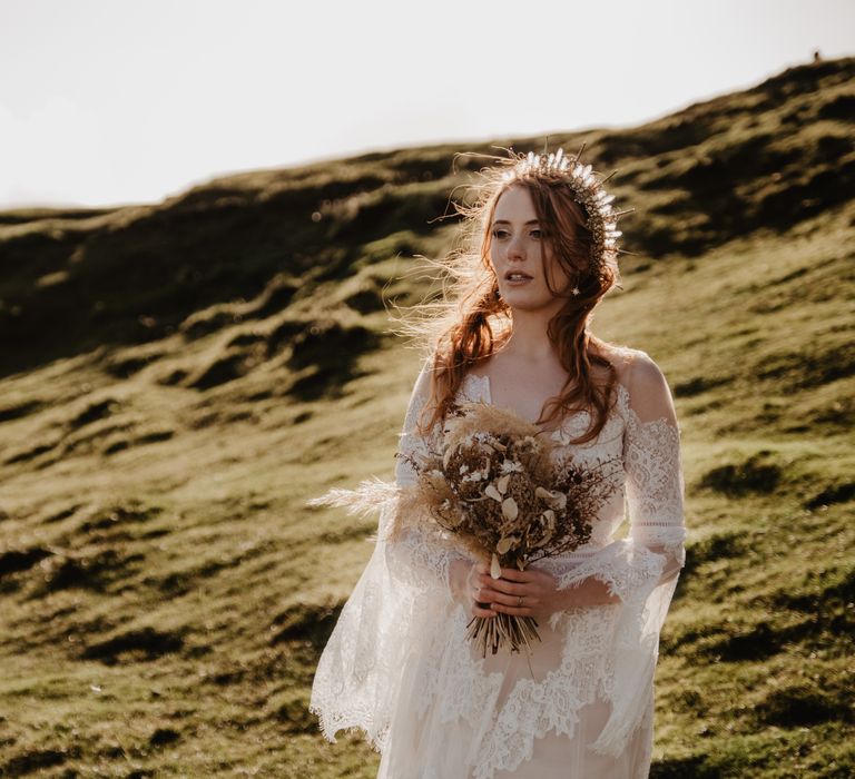 Bride carries floral bouquet across hillside in the Isle Of Skye