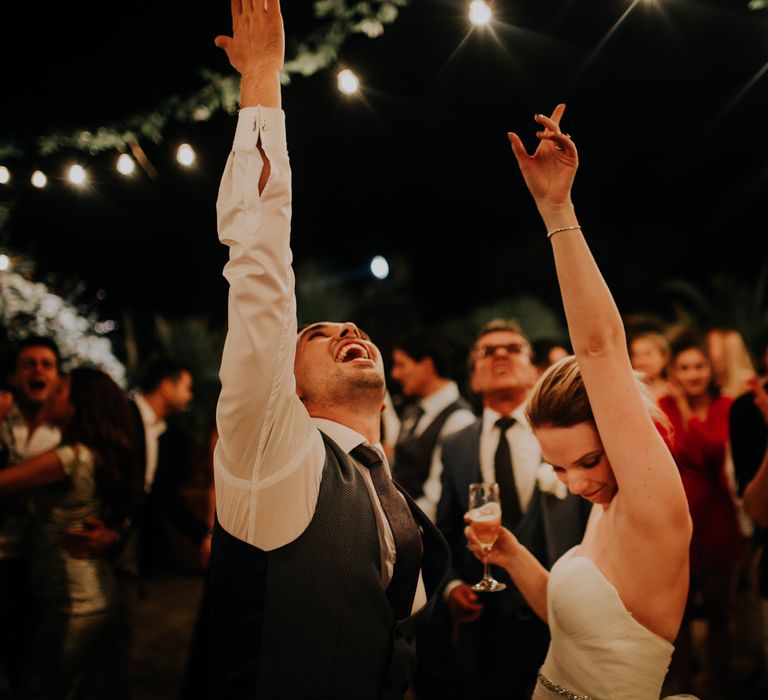 Bride and groom dancing with their hands in the air