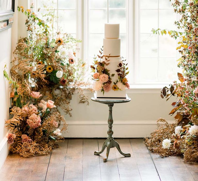 Elegant iced wedding cake surrounded by autumn wedding flowers at Dorfold Hall